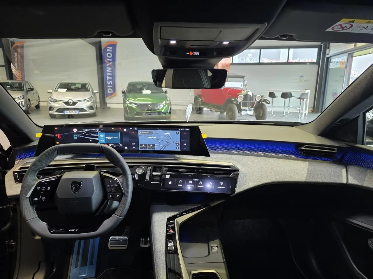 Vue intérieure du tableau de bord du Peugeot 3008 gris titanium 2026, avec écran tactile panoramique et éclairage d'ambiance bleu.
