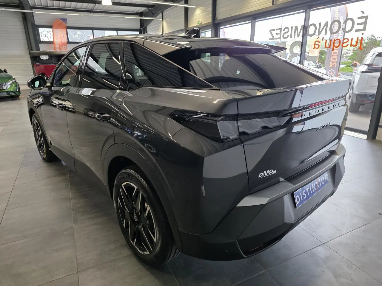 Vue 3/4 arrière droite du Peugeot 3008 gris titanium 2026 en hybride essence, avec feux arrière noirs et jantes noires.