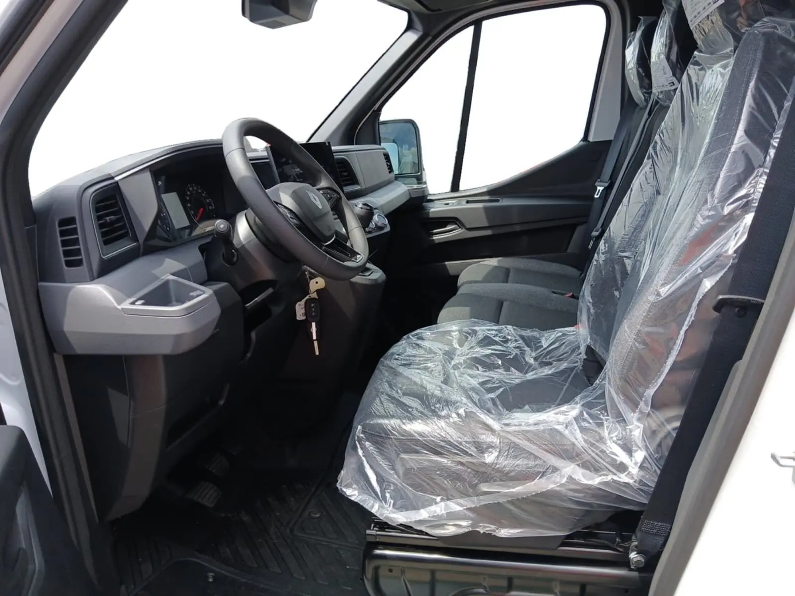 Vue intérieure côté conducteur du Renault Master blanc 2026, montrant le volant, tableau de bord et sièges protégés par film plastique.