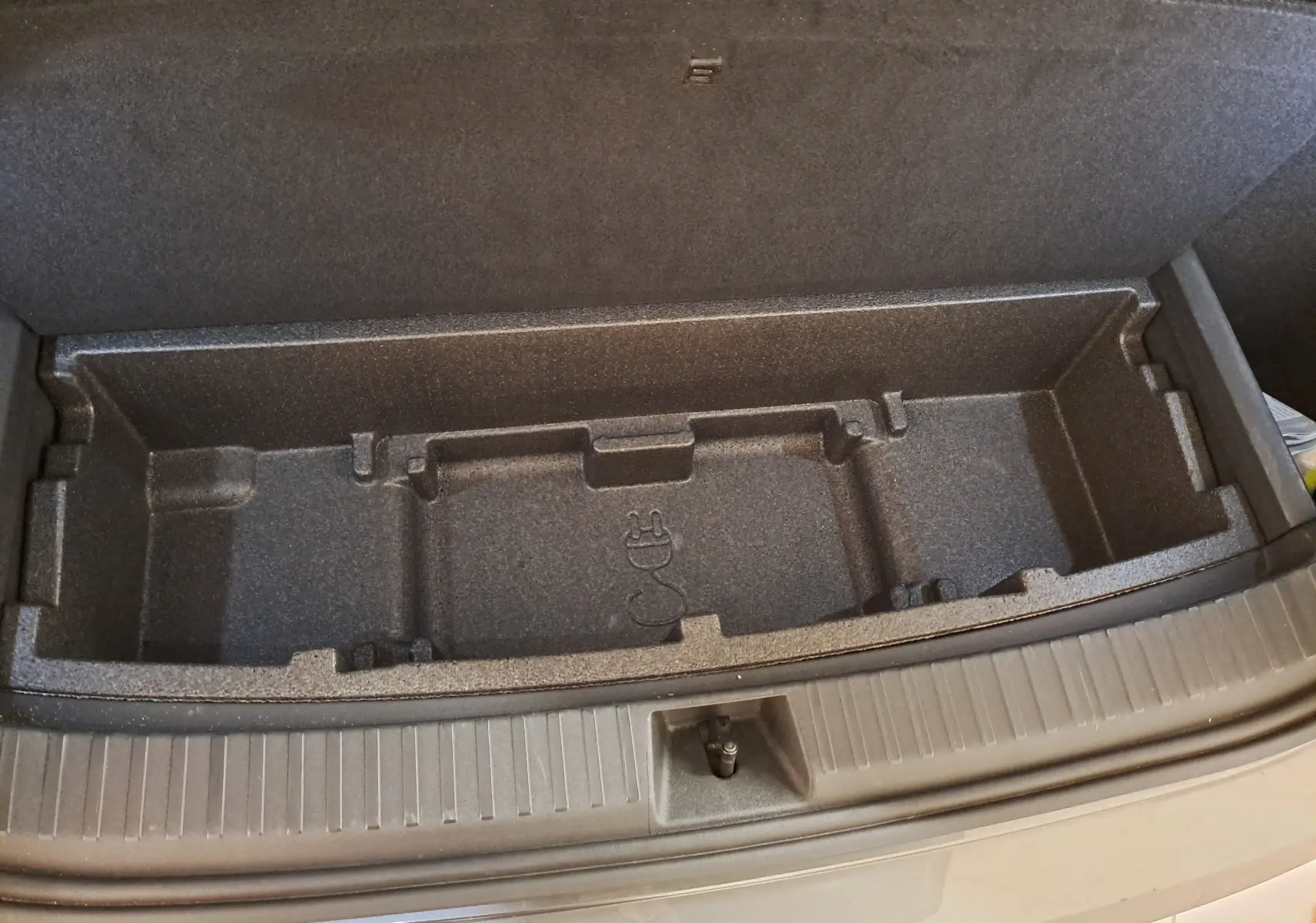 Compartiment de rangement sous le coffre du Skoda Kodiaq gris graphite, vue plongeante sur l'espace vide et compartimenté.