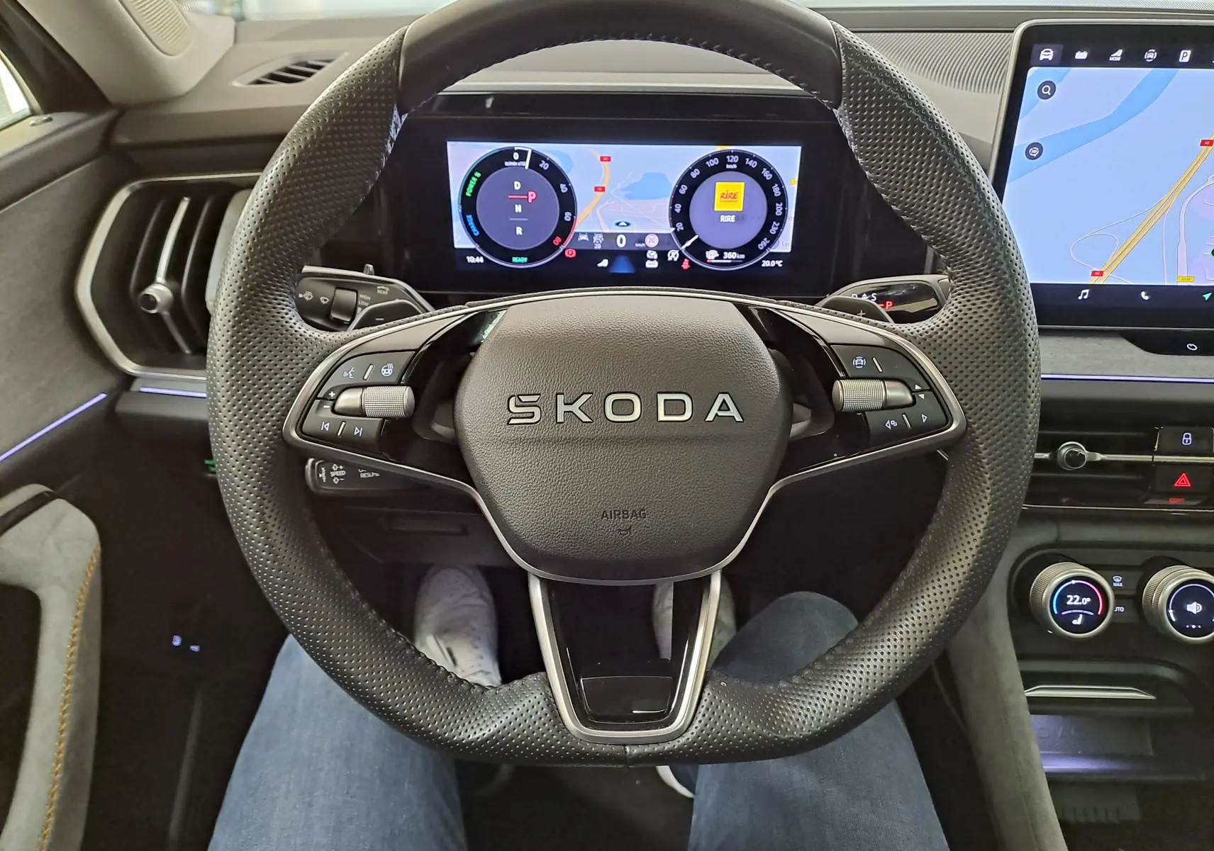 Vue intérieure centrée sur le volant perforé SKODA du KODIAQ 2025 avec tableau de bord numérique et écran tactile latéral.