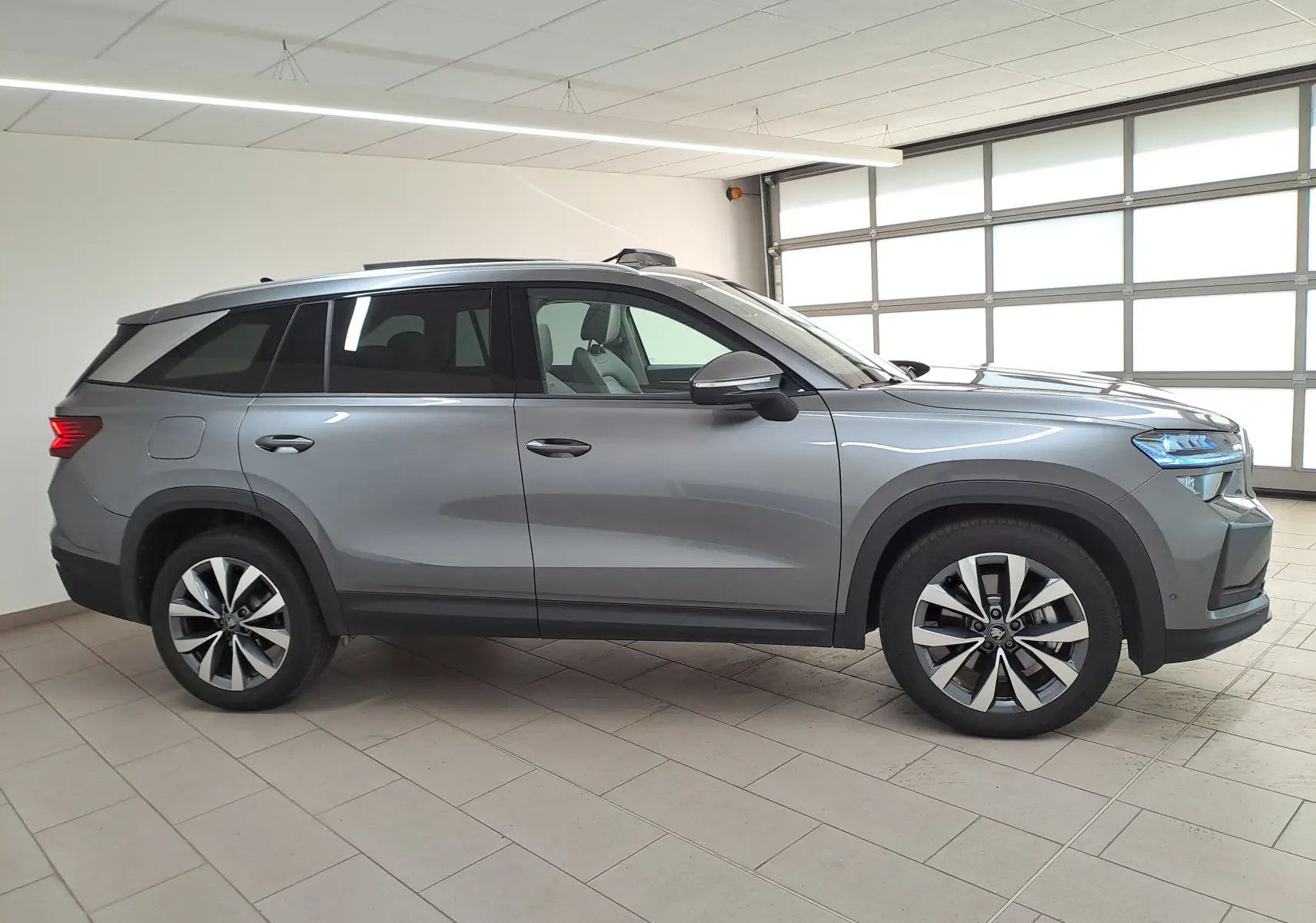 Vue de profil côté gauche d'un Skoda Kodiaq gris graphite 2025 avec jantes alliage 19'' Lefka et toit panoramique ouvrant.