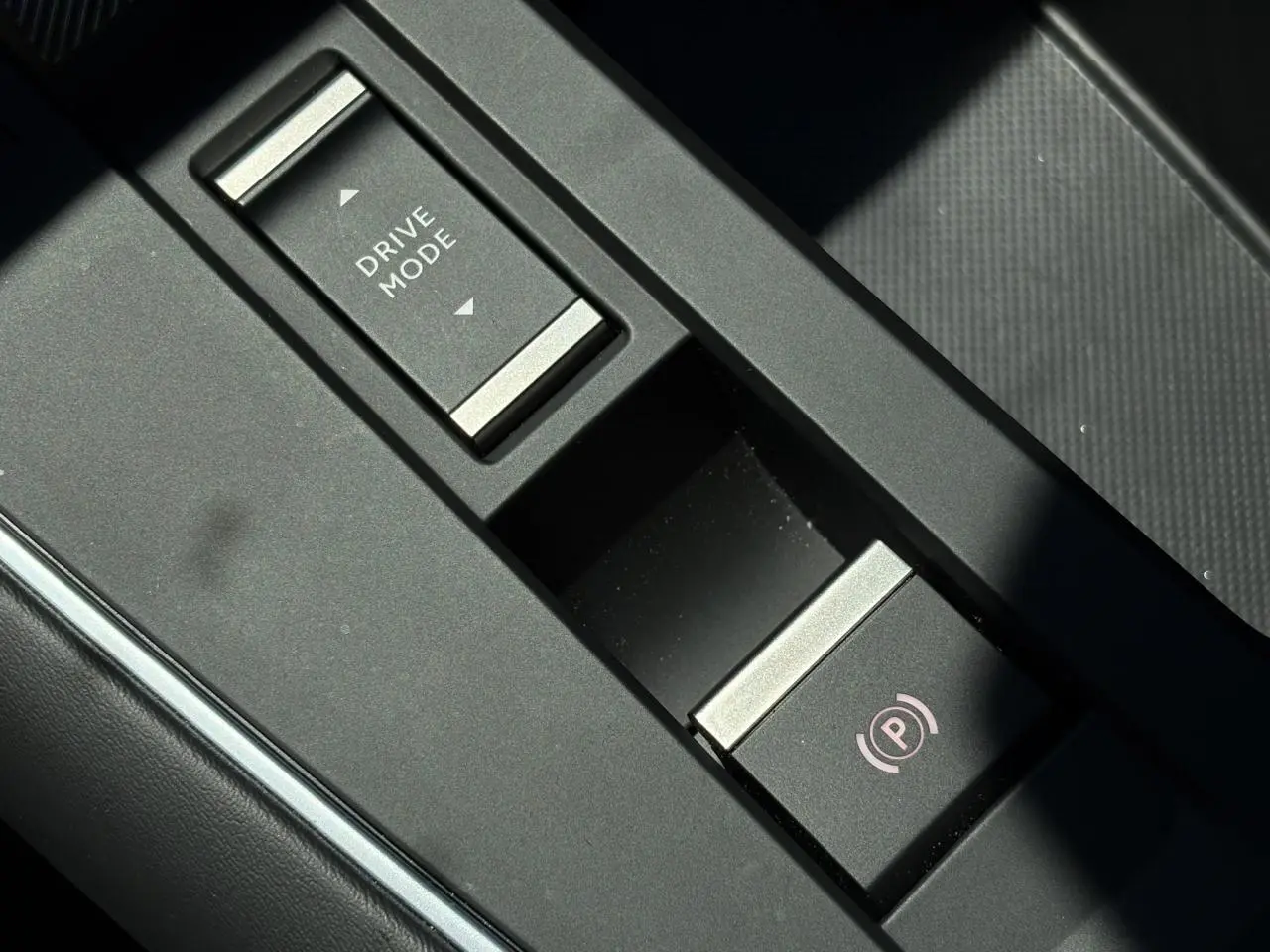 Gros plan sur la console centrale noire du Citroën C5 Aircross Hybrid avec bouton Drive Mode et frein de stationnement électrique.