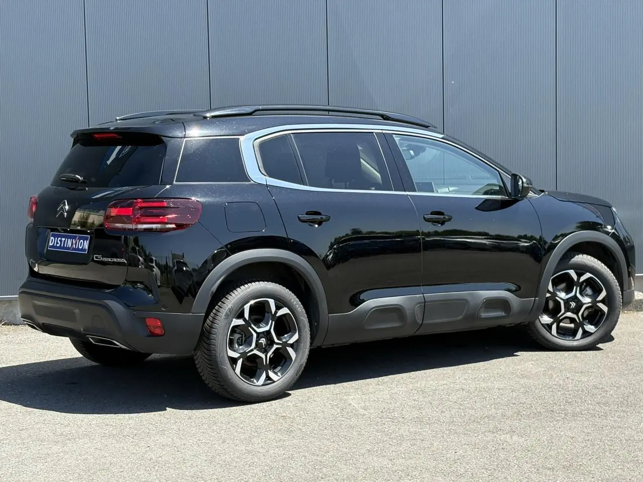 Vue 3/4 arrière droite du Citroën C5 Aircross Hybrid noir Perla avec jantes diamantées et barres de toit noires.