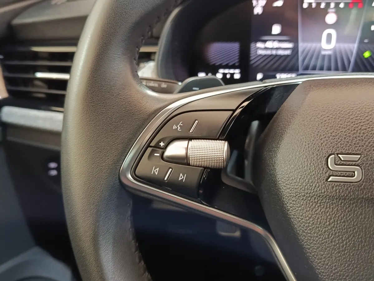 Gros plan sur le volant cuir et alu de la Skoda Scala 2025 avec commandes multifonctions et affichage numérique flou en arrière-plan.