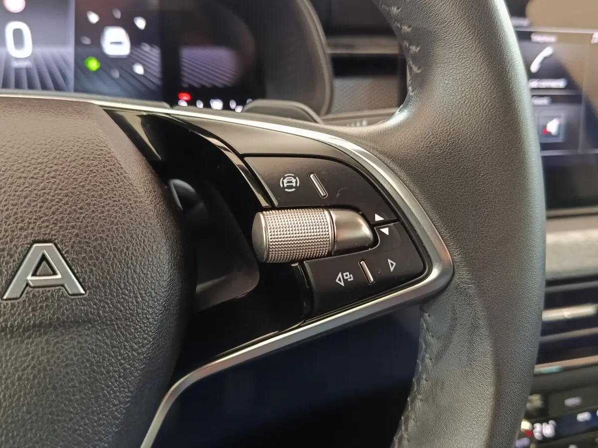 Gros plan sur la commande multifonction droite du volant cuir noir de la Skoda Scala bleu, avec molette métallique texturée.