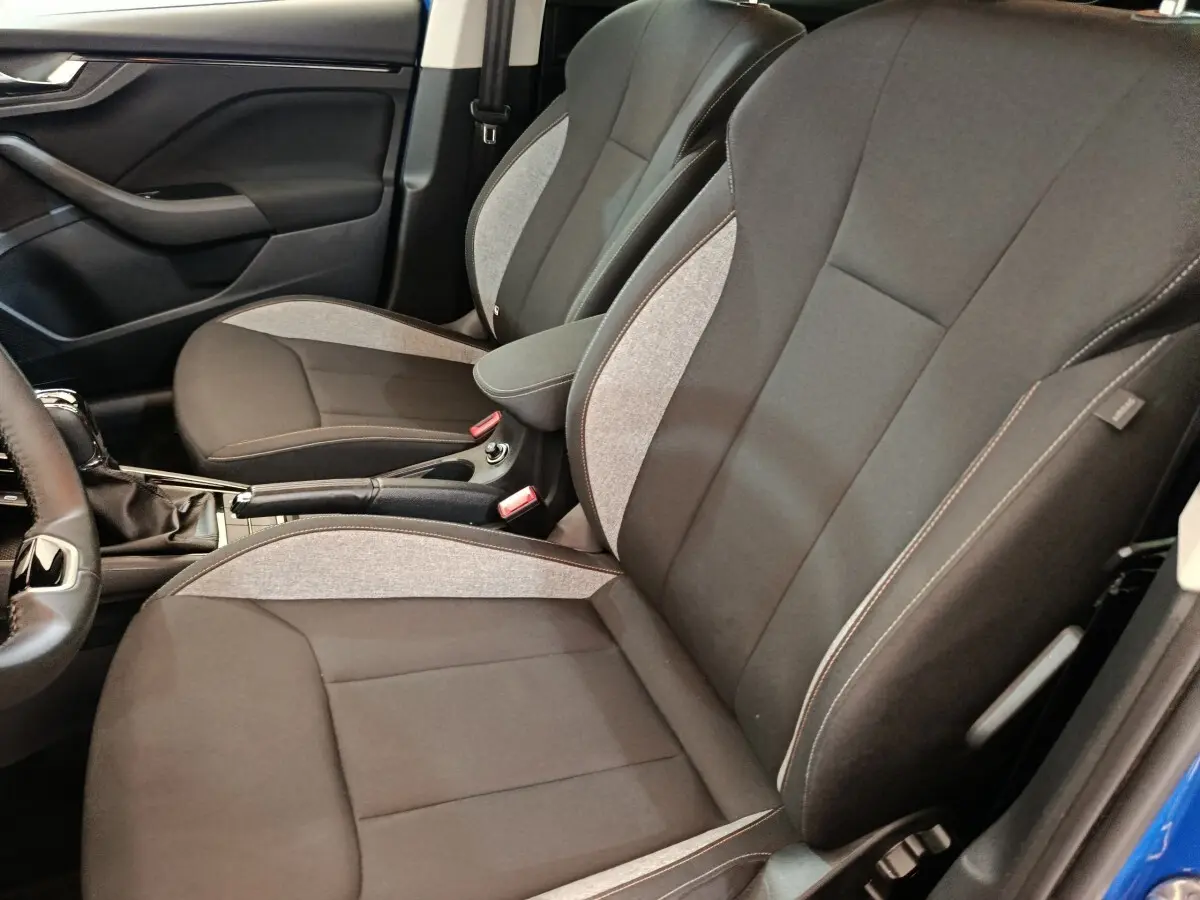 Vue intérieure côté gauche des sièges avant gris et noir de la Skoda Scala 1.0 TSI 2025 avec accoudoir central.