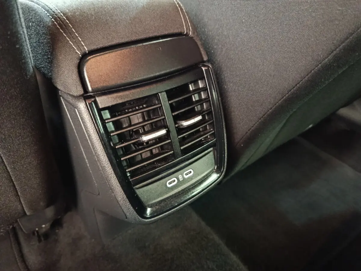 Vue rapprochée des aérateurs arrière noirs avec deux ports USB-C sur la console centrale arrière d'une Skoda Scala bleue.