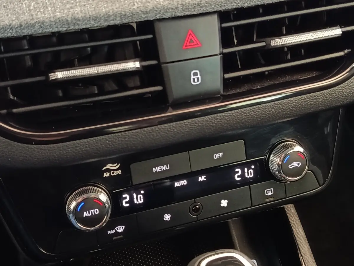 Gros plan sur la console centrale noire du Skoda Scala 2025, avec commandes de climatisation digitale affichant 21°C.