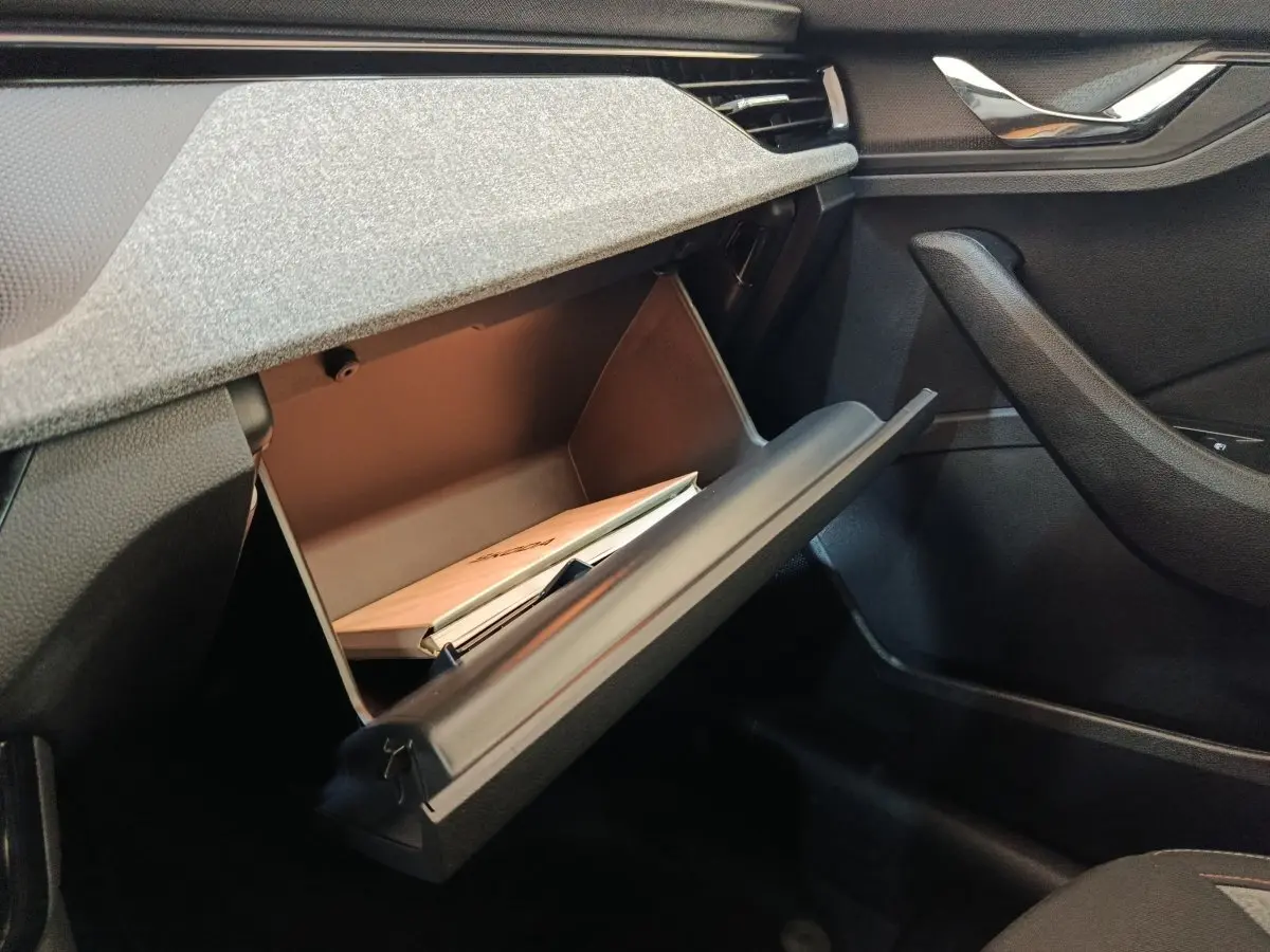 Vue intérieure côté passager du coffre à gants ouvert d'une Skoda Scala 2025 bleu, avec documents visibles à l'intérieur.