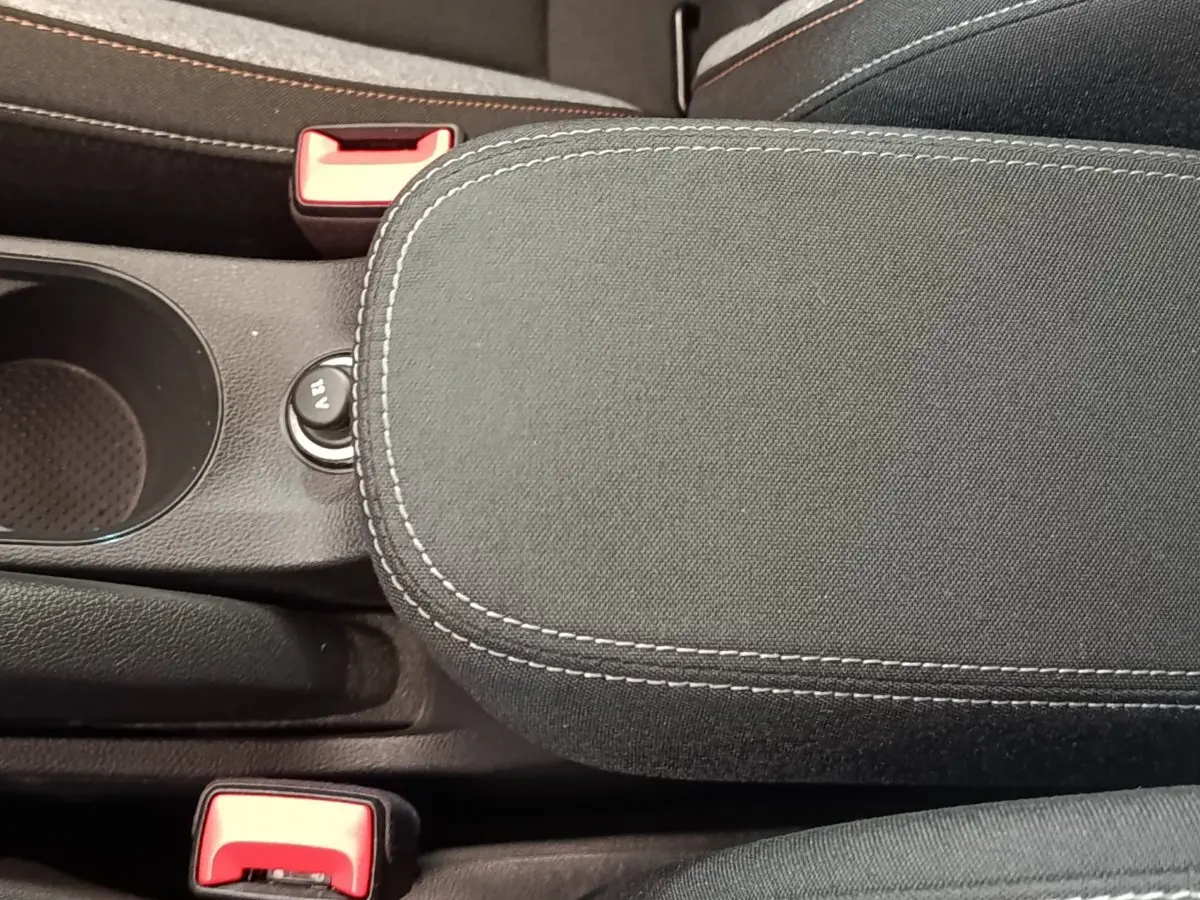 Vue rapprochée de l'accoudoir central noir avec surpiqûres blanches et prise 12V visible sur la Skoda Scala 2025.