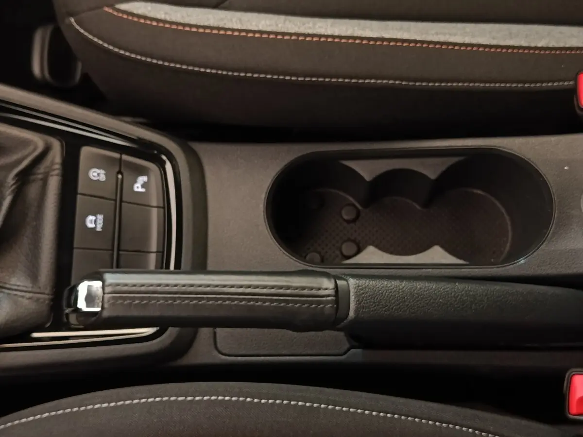 Vue plongeante sur la console centrale de la Skoda Scala 2025, frein à main cuir et porte-gobelets noirs.