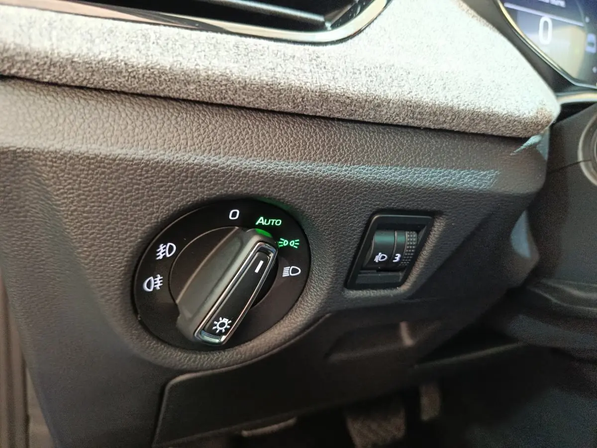 Gros plan sur la commande des phares avec réglage automatique dans l’habitacle du Skoda Scala bleu 2025.