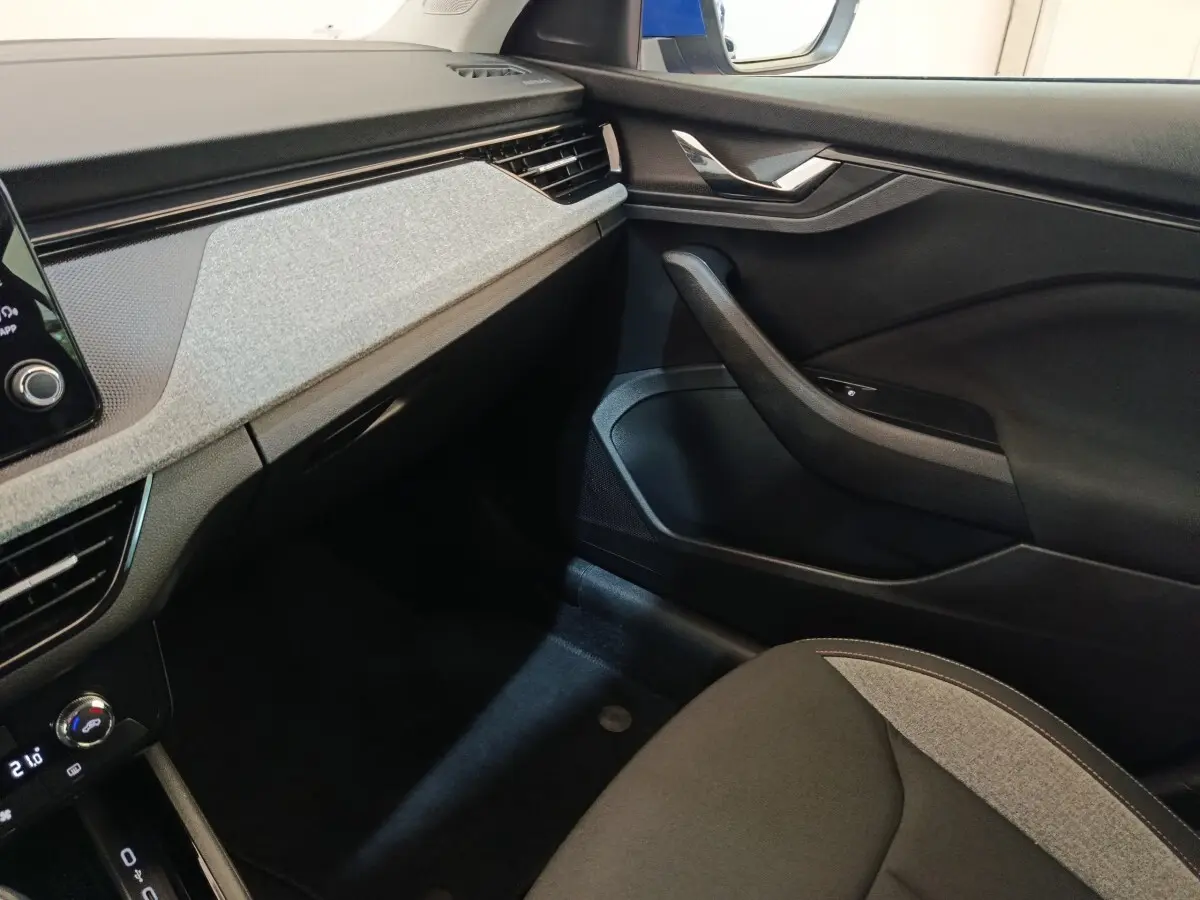 Intérieur avant droit du Skoda Scala 2025, tableau de bord gris clair avec détails noirs et siège tissu bicolore.