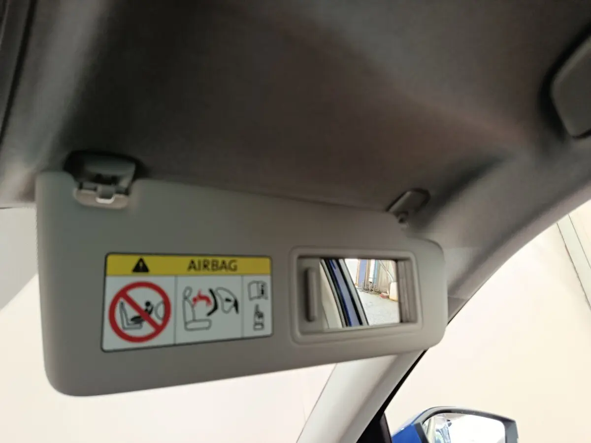 Détail du pare-soleil côté conducteur avec miroir, montrant un reflet du rétroviseur extérieur bleu de la Skoda Scala.