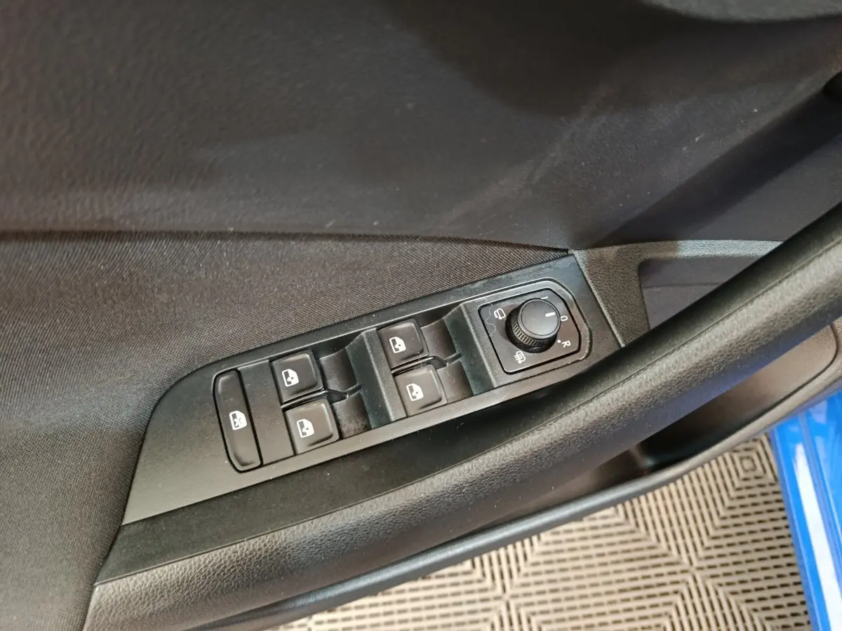 Vue rapprochée des commandes de lève-vitres et réglage des rétroviseurs sur la porte côté gauche d’une Skoda Scala bleue.