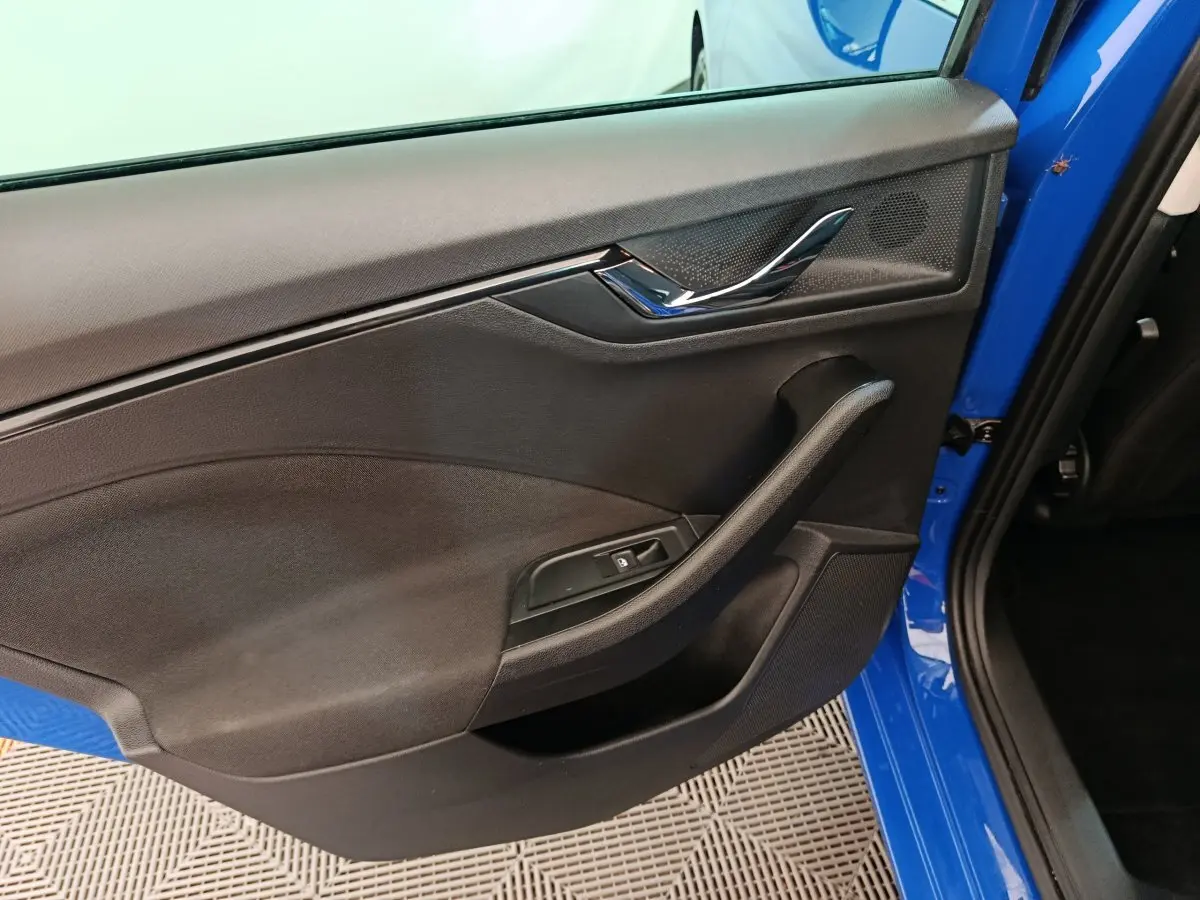 Vue intérieure de la porte arrière gauche d'une Skoda Scala bleu 2025 avec poignée et commande de vitre noire.