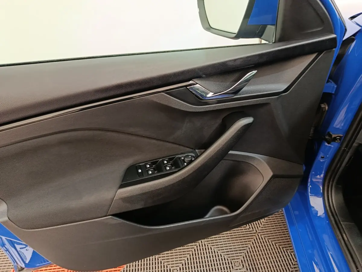 Vue intérieure côté gauche de la porte avant bleue d'une Skoda Scala avec commandes de vitres et poignée chromée.