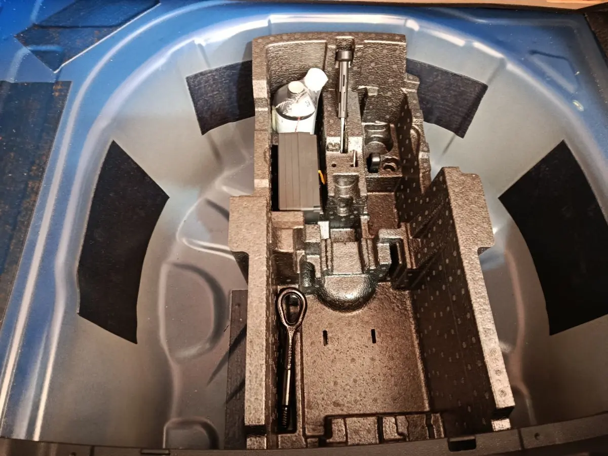 Vue plongeante sur la roue de secours galette et son rangement en mousse dans le coffre d'une Skoda Scala bleu 2025.