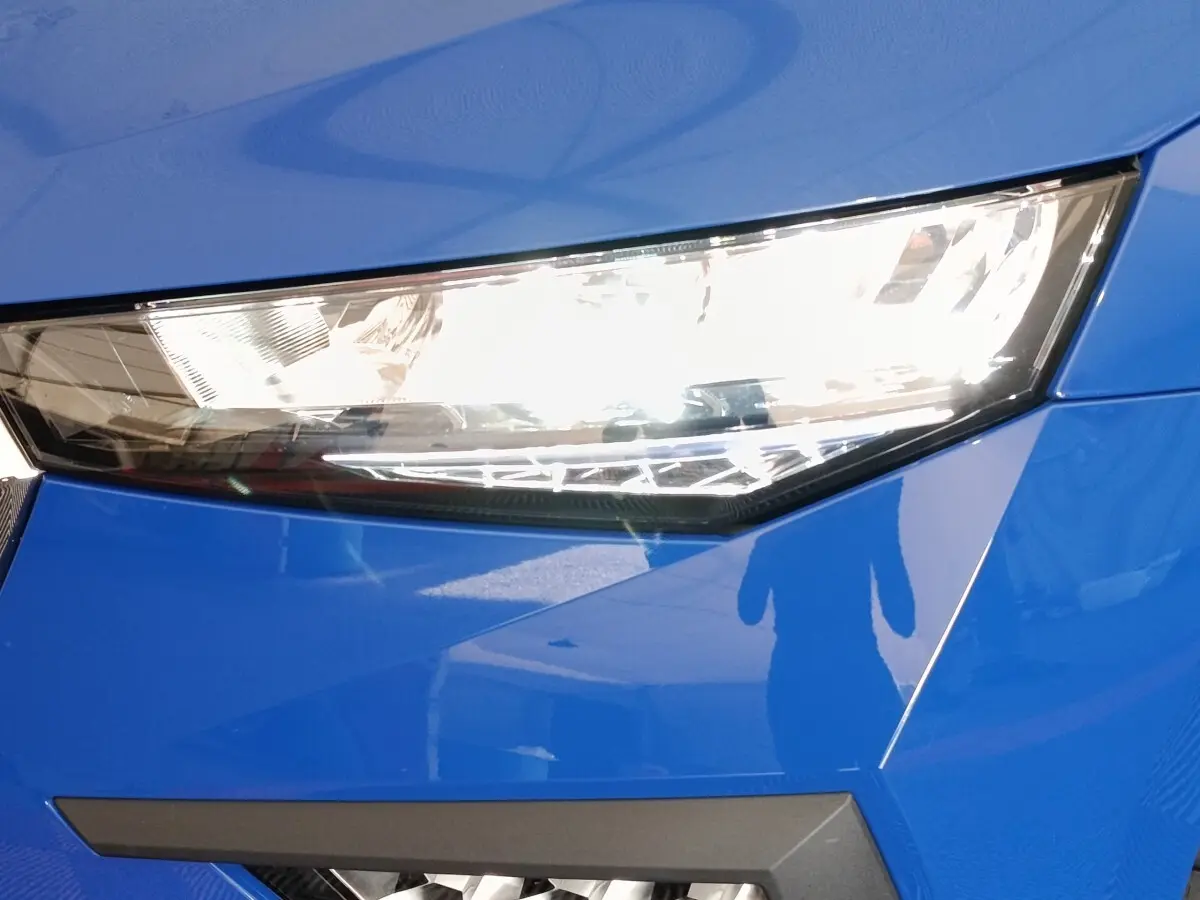 Gros plan sur le phare avant droit d'une Skoda Scala bleu électrique avec lignes anguleuses et finition brillante.