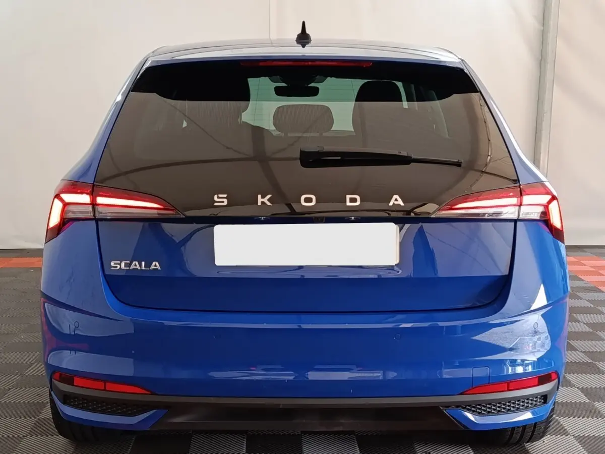 Vue arrière d'une Skoda Scala bleue 2025 avec feux LED et logo SKODA lumineux sur hayon noir.