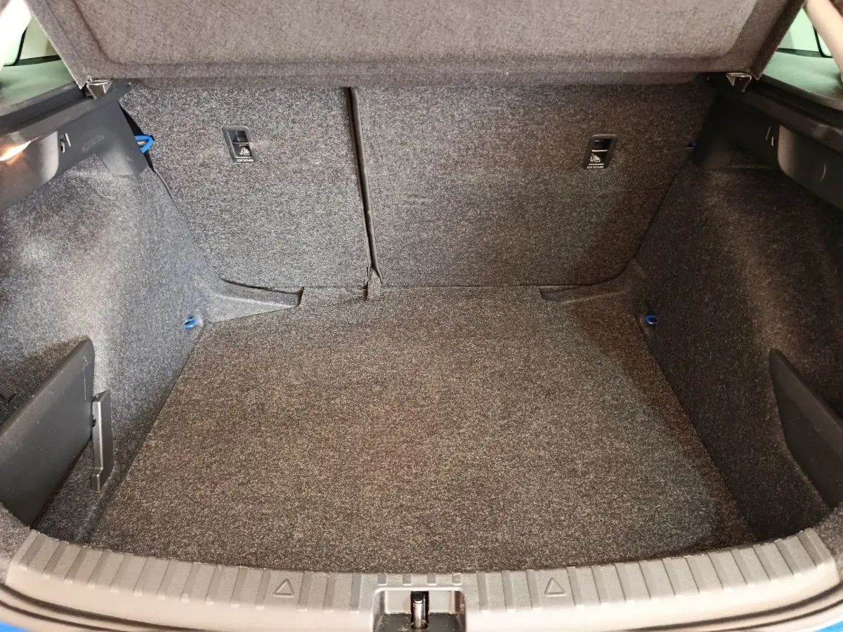 Coffre ouvert vu de face d'une Skoda Scala 1.0 TSI bleu, montrant un espace de chargement tapissé gris.