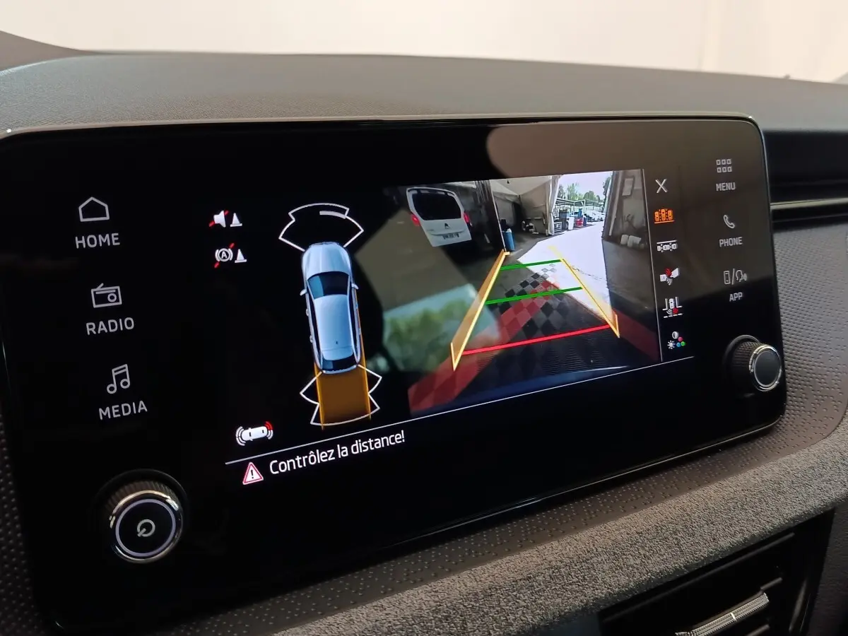 Écran tactile central du Skoda Scala bleu 2025 montrant la caméra de recul avec guidage de trajectoire.