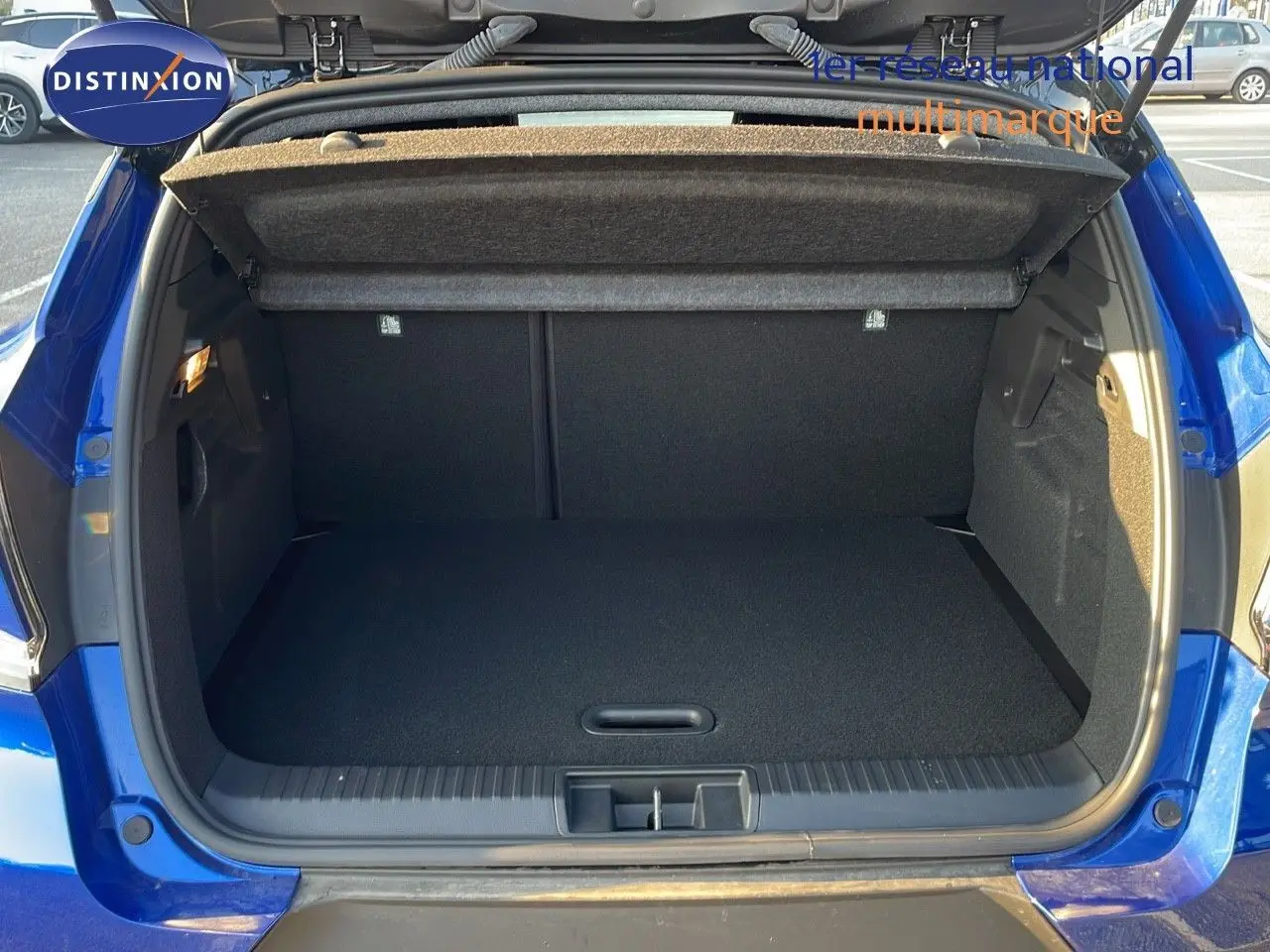 Coffre ouvert d'un Renault Captur E-Tech hybride bleu Iron Metal avec toit noir, vue arrière montrant l'espace de chargement.