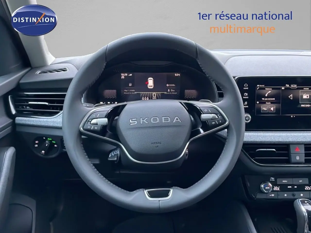 Vue intérieure centrée sur le volant SKODA du KAMIQ, tableau de bord numérique et écran tactile visibles.