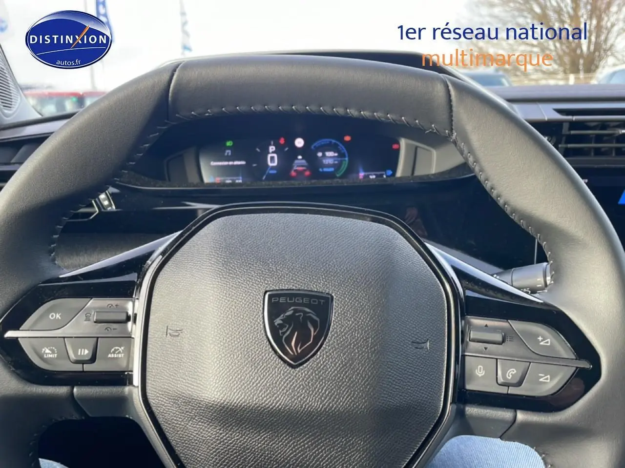 Vue rapprochée du volant multifonction noir de la Peugeot 308 1.2 hybrid 145 allure e-dcs6 avec tableau de bord numérique en arrière-plan.