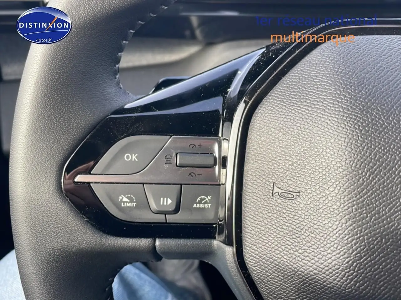 Gros plan sur les commandes au volant côté gauche du Peugeot 308 gris artense, version 1.2 hybrid 145 allure e-dcs6.