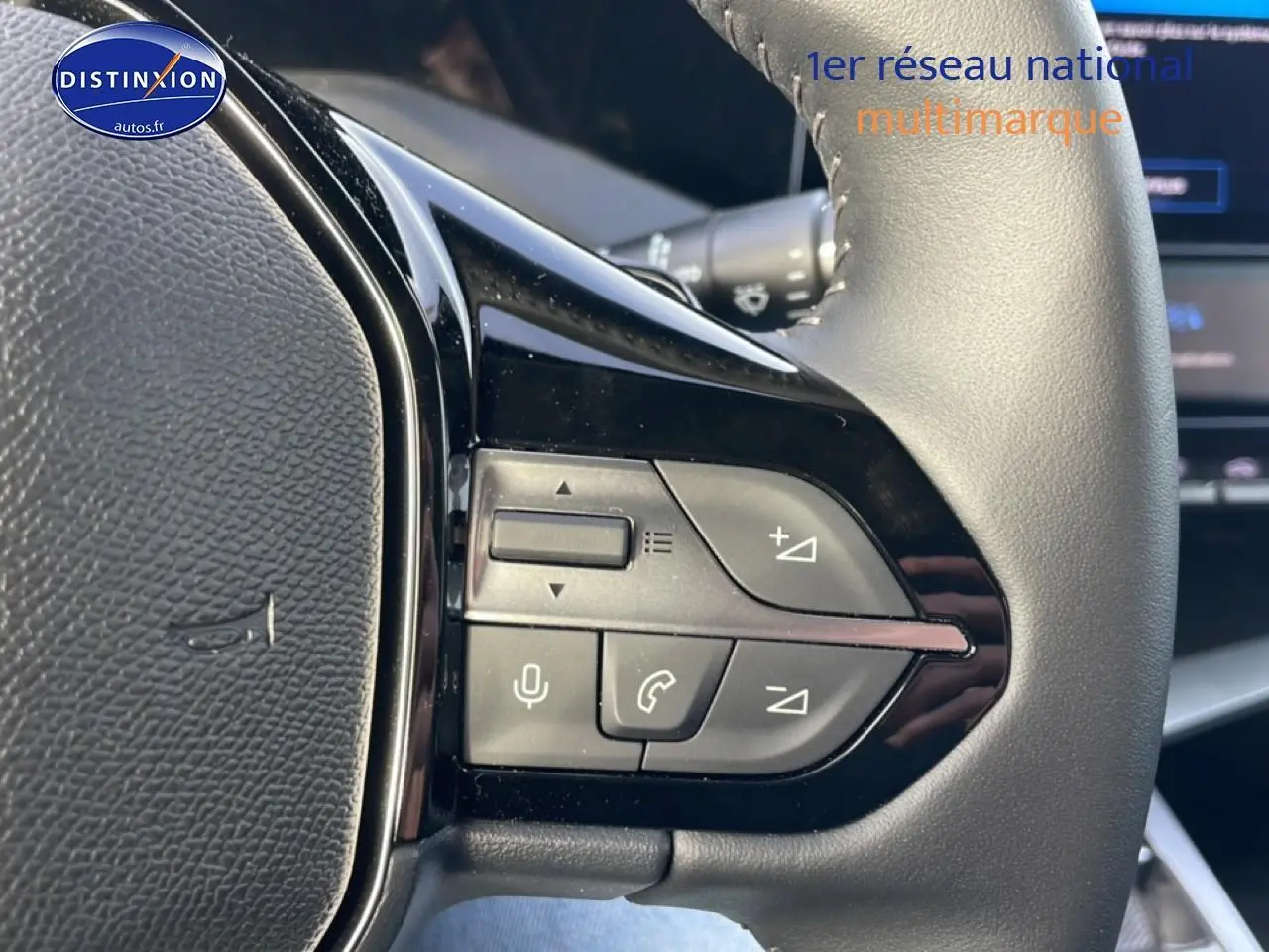 Gros plan sur les commandes multifonctions du volant cuir noir de la Peugeot 308 gris Artense, version 2025.