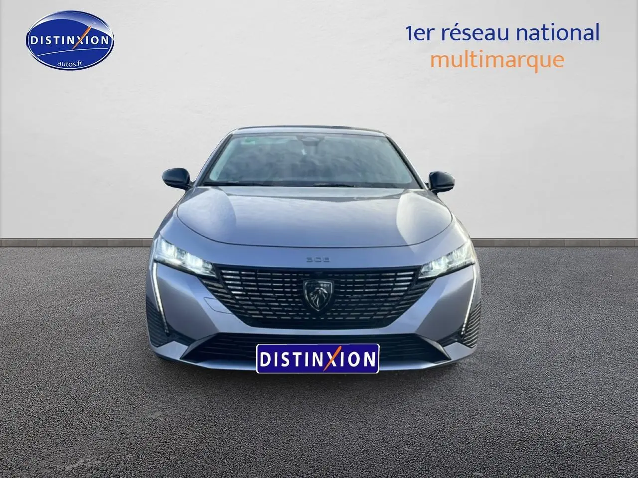 Vue avant frontale de la Peugeot 308 1.2 hybrid 145 allure gris artense avec calandre noire et phares LED allumés.