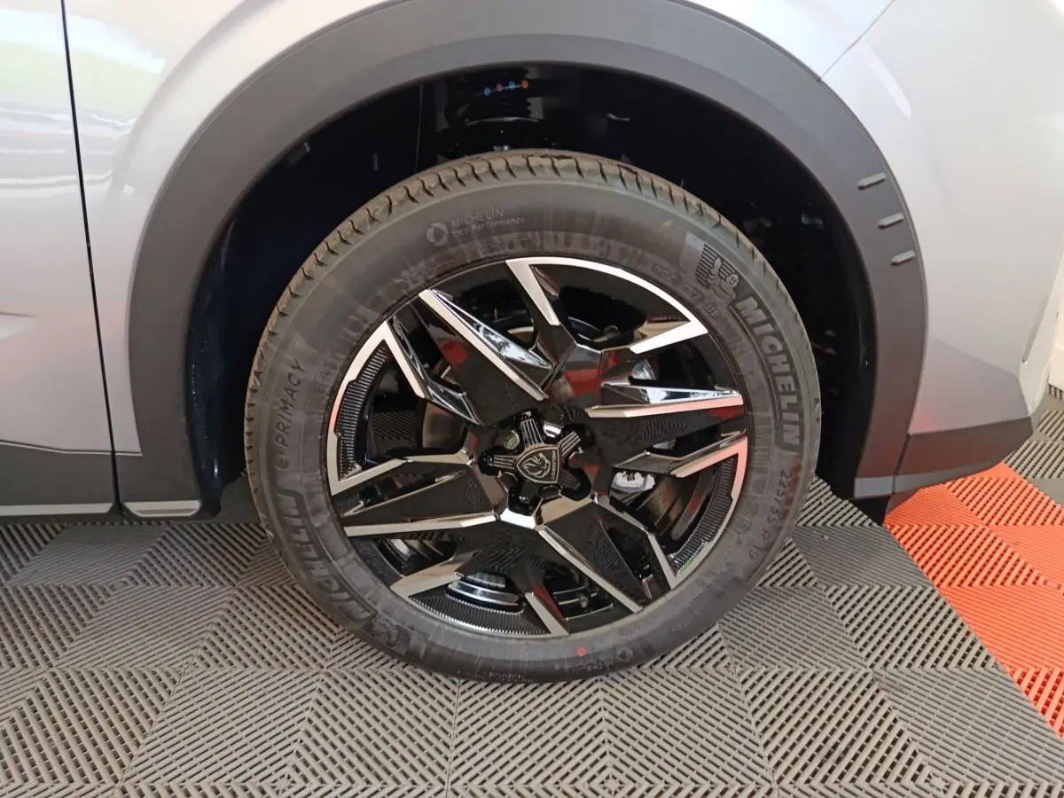Gros plan sur la roue avant gauche du Peugeot 3008 gris clair, avec jante alliage noire et détails chromés.