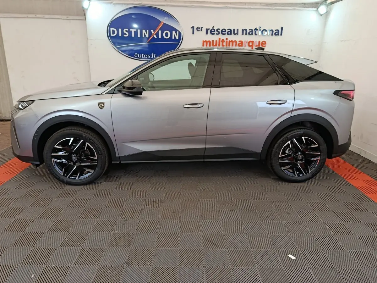 Profil droit du Peugeot 3008 gris clair 2025 avec jantes noires et toit noir contrasté en intérieur showroom.