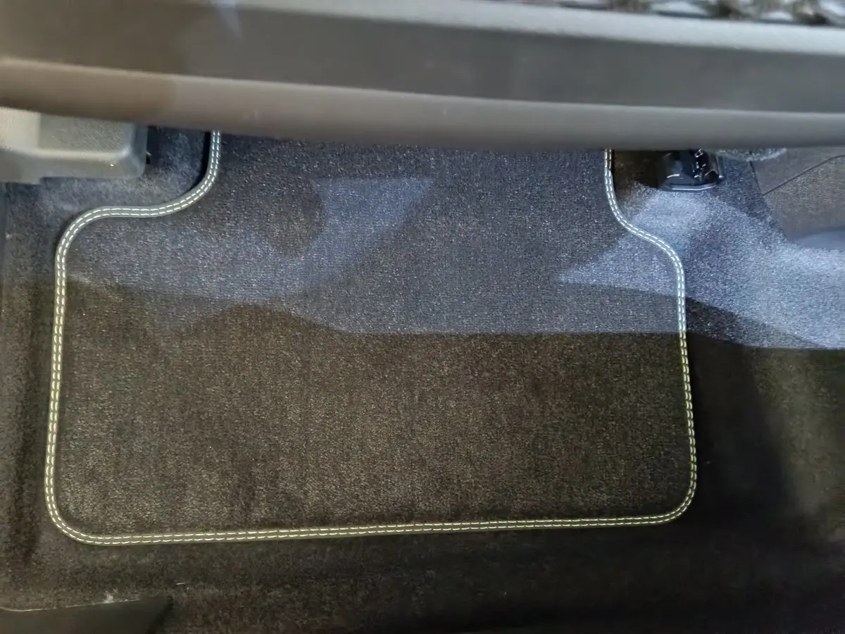 Tapis de sol noir avec surpiqûres blanches dans l'habitacle avant d'un Peugeot 3008 gris clair hybride 2025.