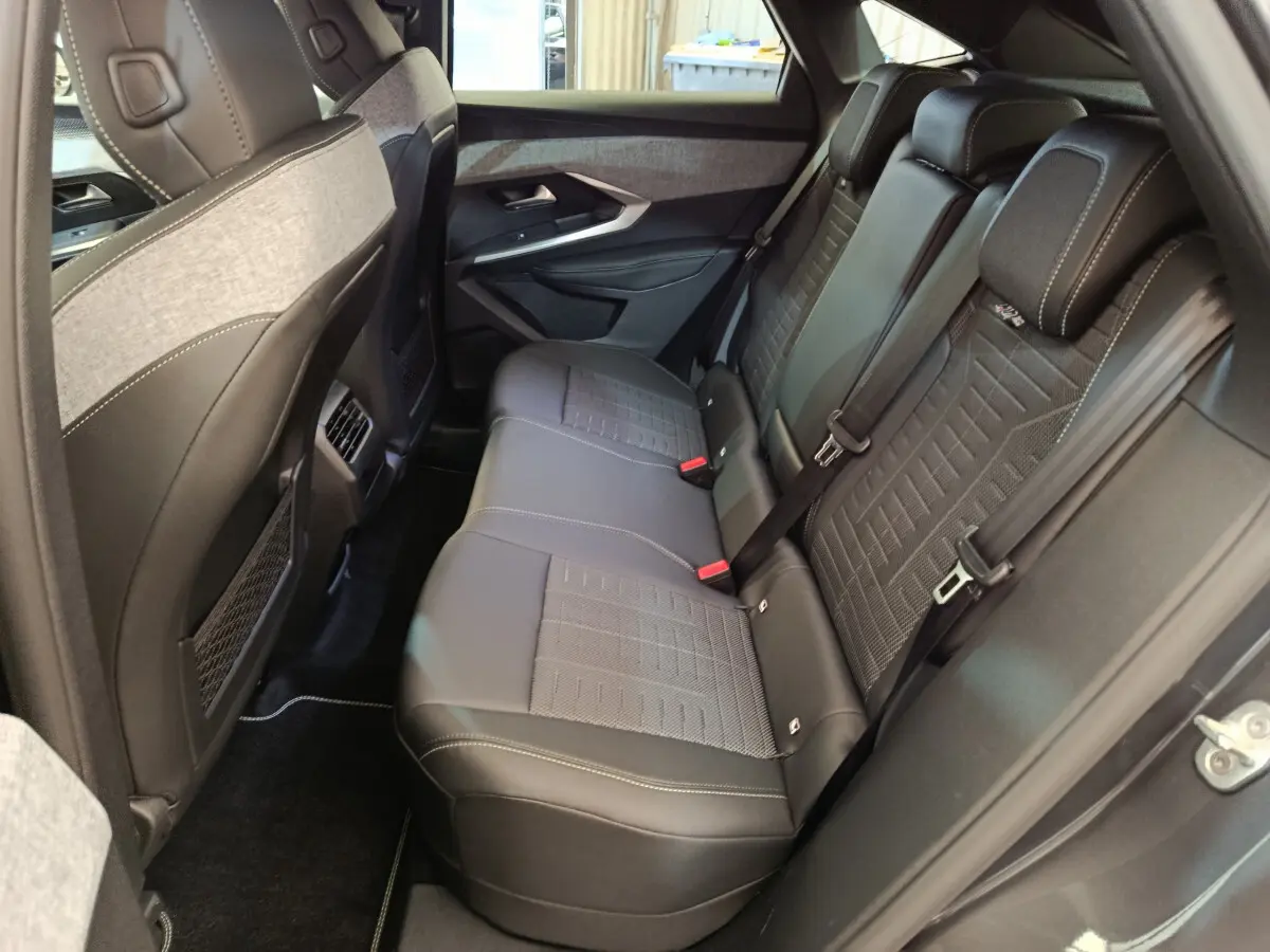 Vue côté droit de l’habitacle arrière du Peugeot 3008 gris clair, sièges en cuir noir avec surpiqûres blanches.