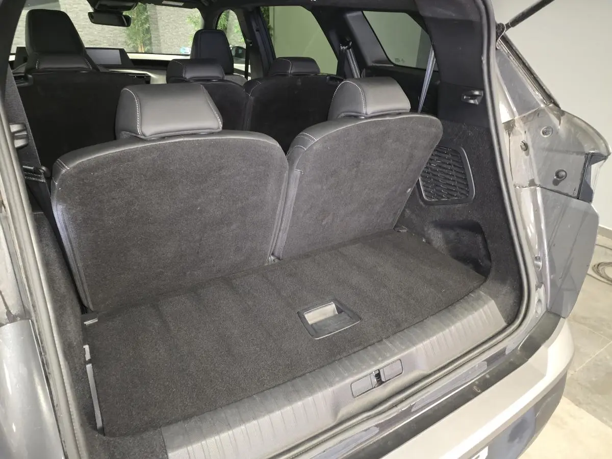 Coffre ouvert du Peugeot 5008 gris 2025, montrant la banquette arrière rabattue et l'intérieur noir.