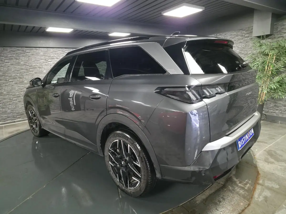 Vue 3/4 arrière droite d’un Peugeot 5008 gris métallisé avec jantes alliage noires et bandeau noir laqué entre feux arrière.