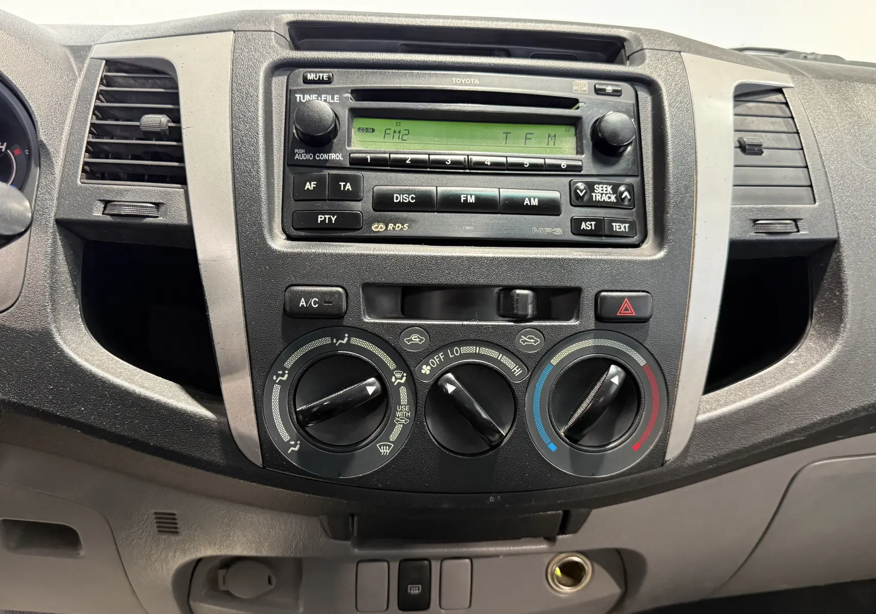 Tableau de bord du Toyota Hilux X-Tra Cabine 2009, vue frontale centrée sur la radio et les commandes de climatisation.