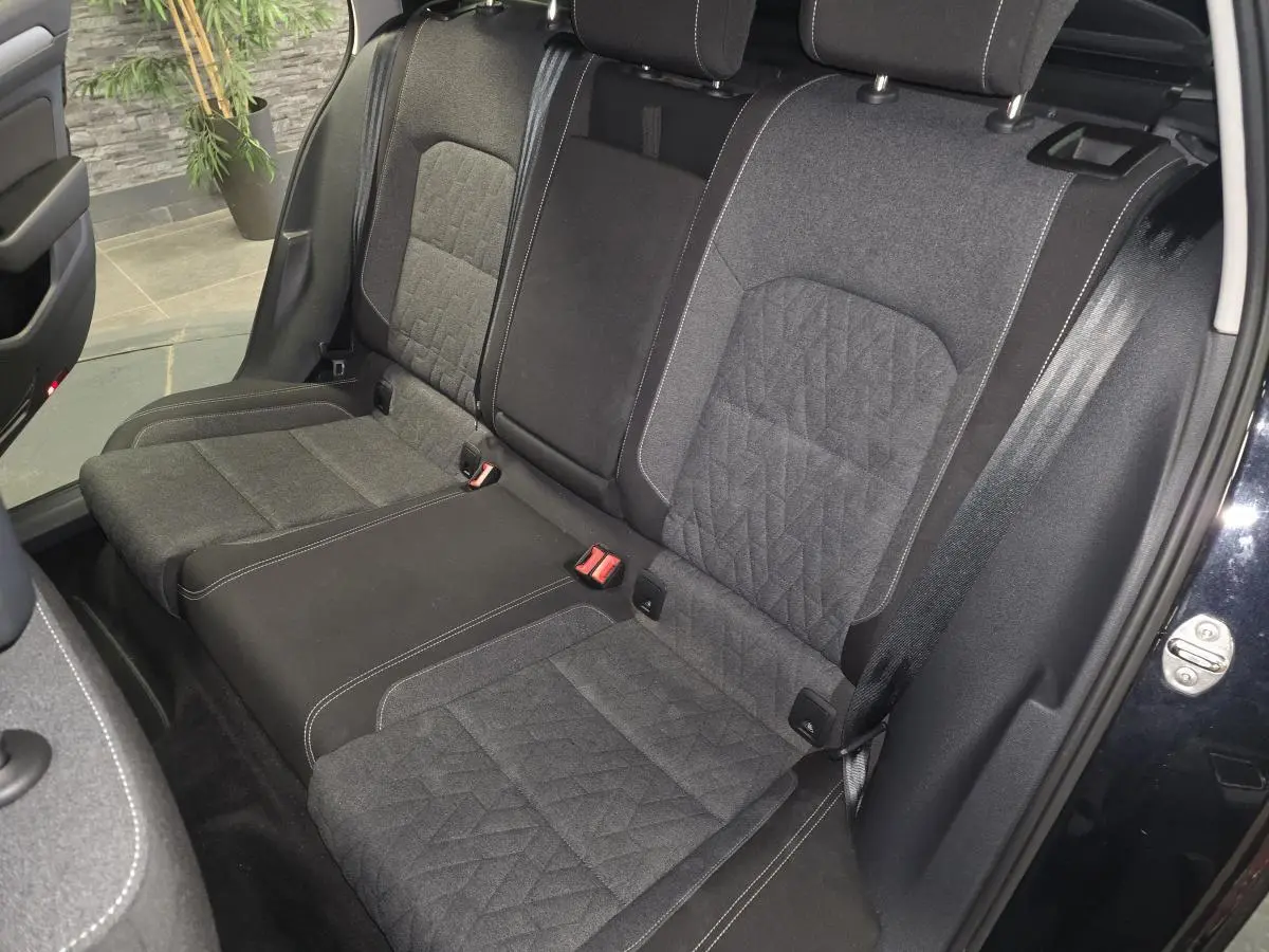 Vue intérieure côté arrière droit de la banquette tissu gris foncé avec surpiqûres blanches de la Volkswagen Passat SW noire 2024.
