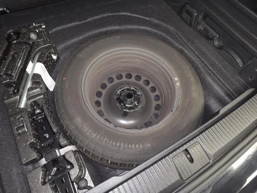 Vue rapprochée du coffre de la Volkswagen Passat SW 2024 montrant la roue de secours et les outils de changement de pneu.