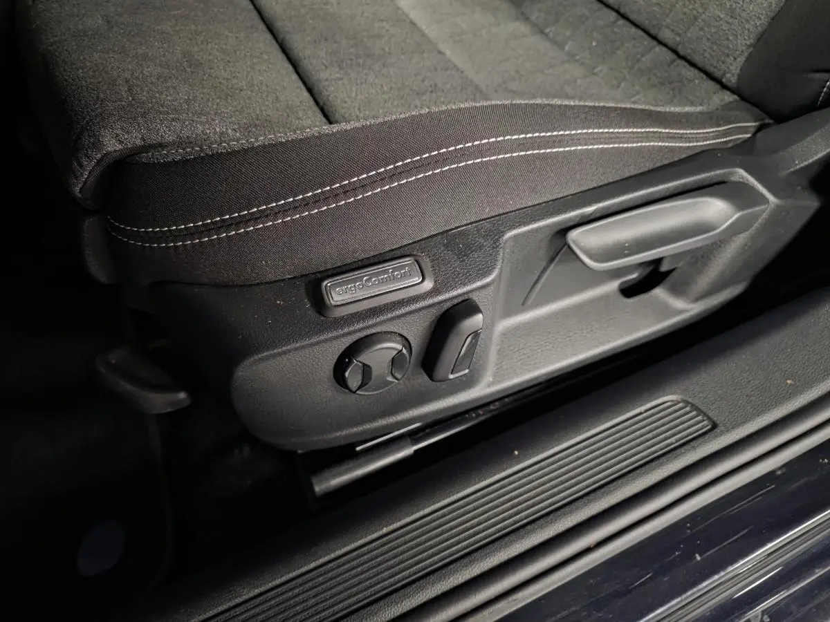 Détail des commandes de réglage du siège avant en tissu noir de la Volkswagen Passat SW 2024 côté gauche.