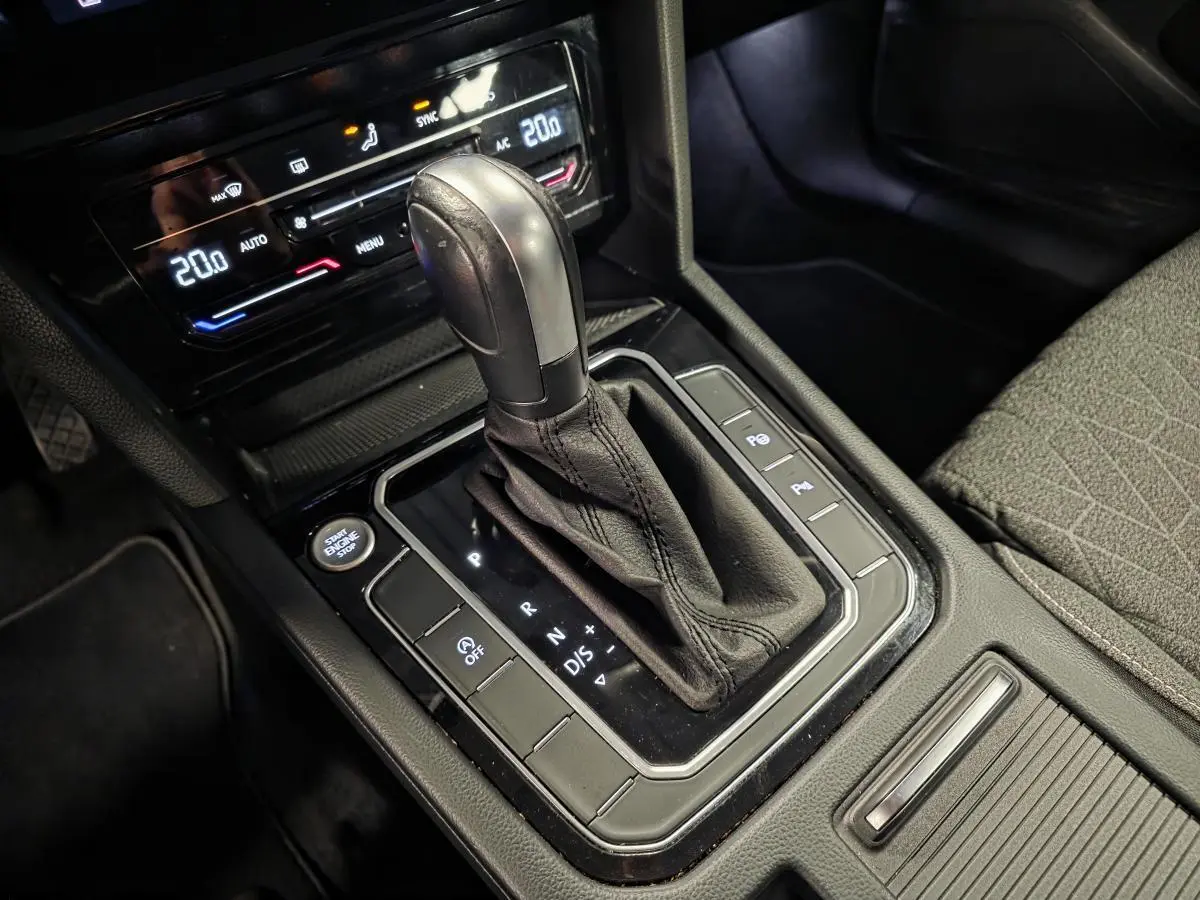 Gros plan sur la console centrale noire de la Volkswagen Passat SW 2024, mettant en valeur le levier de vitesse automatique et les commandes adjacentes.