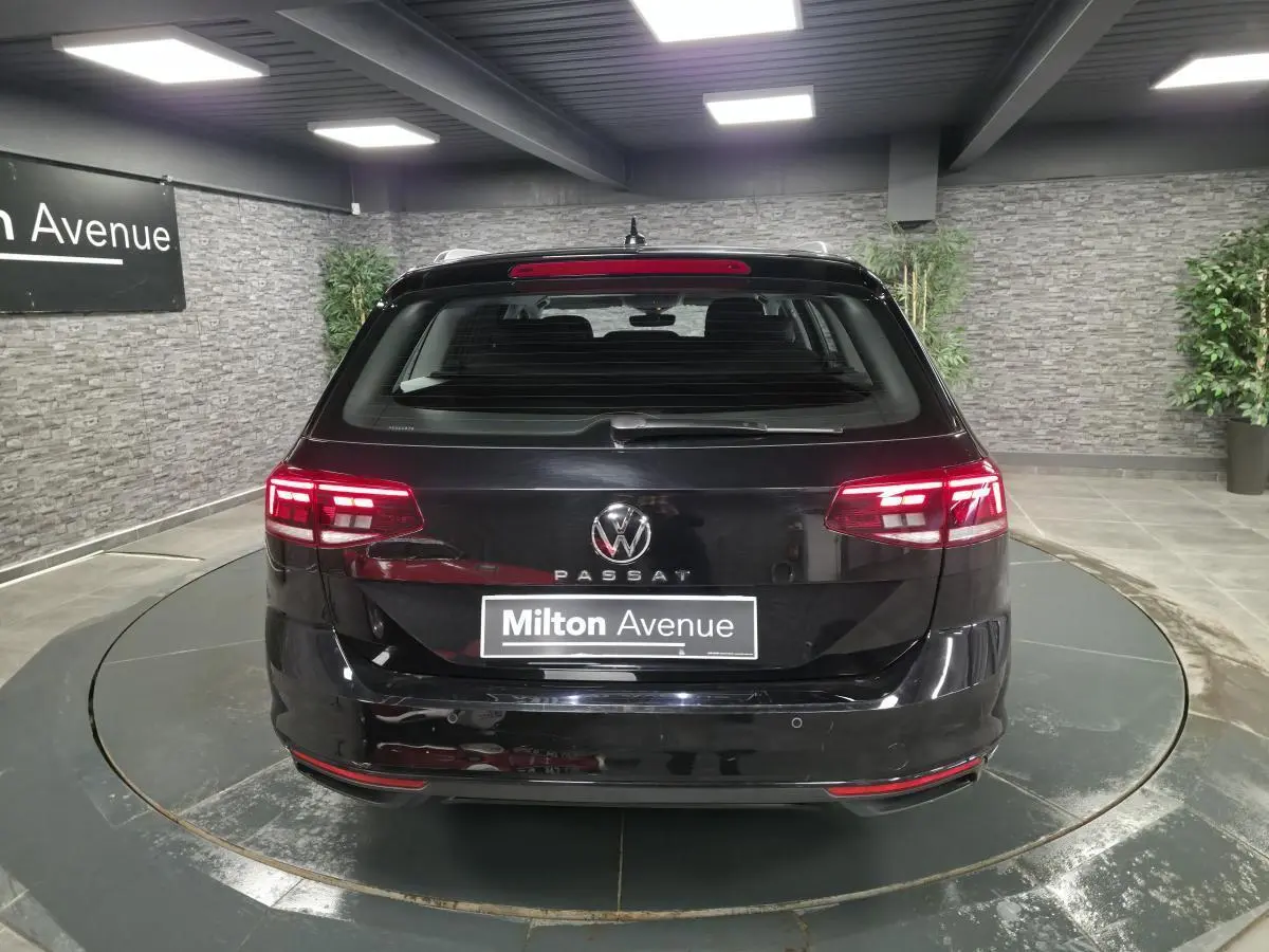 Vue arrière d'une Volkswagen Passat SW noire avec feux LED allumés dans un showroom intérieur.