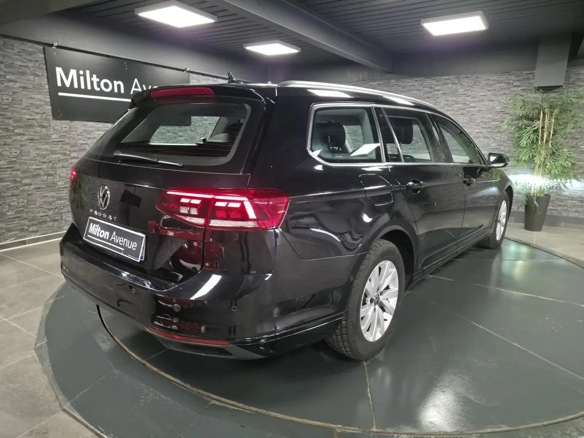 Vue 3/4 arrière droite d'une Volkswagen Passat SW noire avec feux arrière LED allumés en showroom.