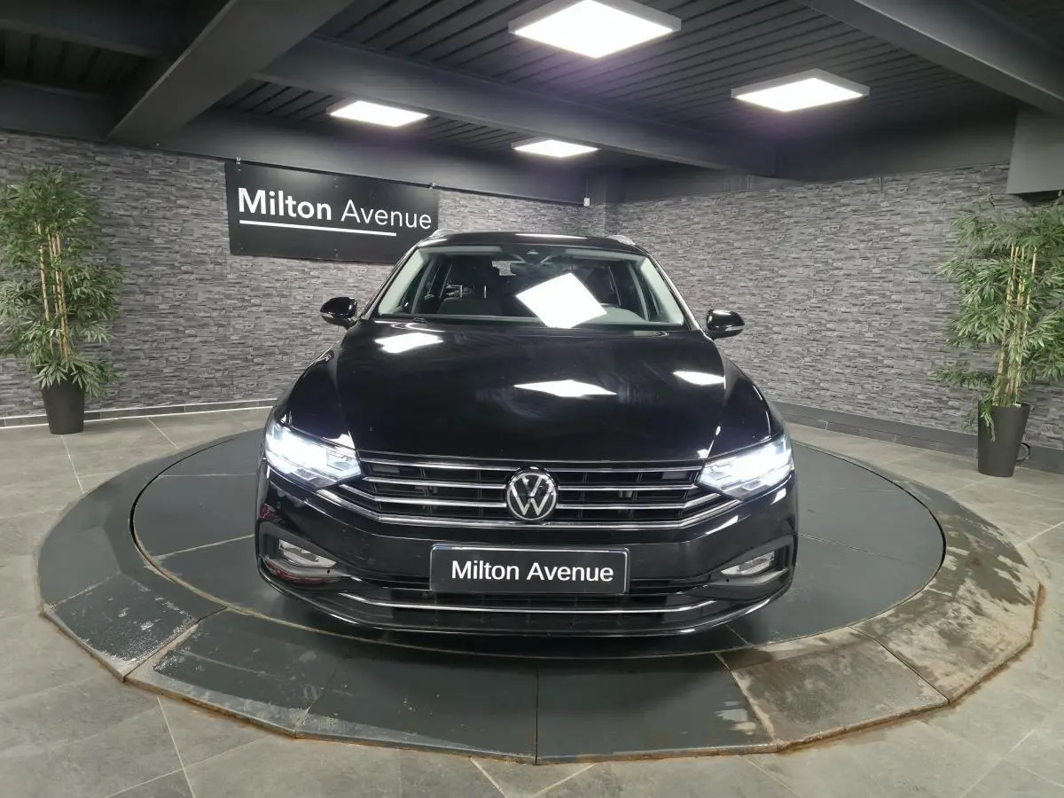 Vue avant d'une Volkswagen Passat SW noire avec phares allumés sur plateau tournant intérieur.