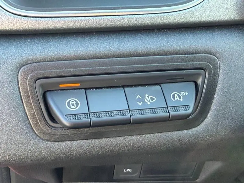 Gros plan sur les boutons de commande intérieurs noirs du Renault Captur rouge, avec indicateur orange allumé.