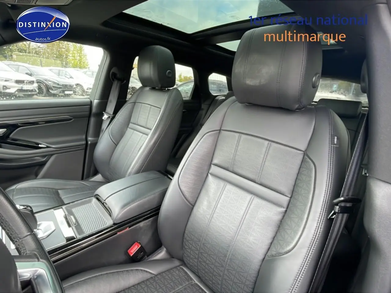 Vue intérieure sur les sièges avant en cuir noir du Range Rover Evoque 2020 avec toit panoramique et accoudoir central.