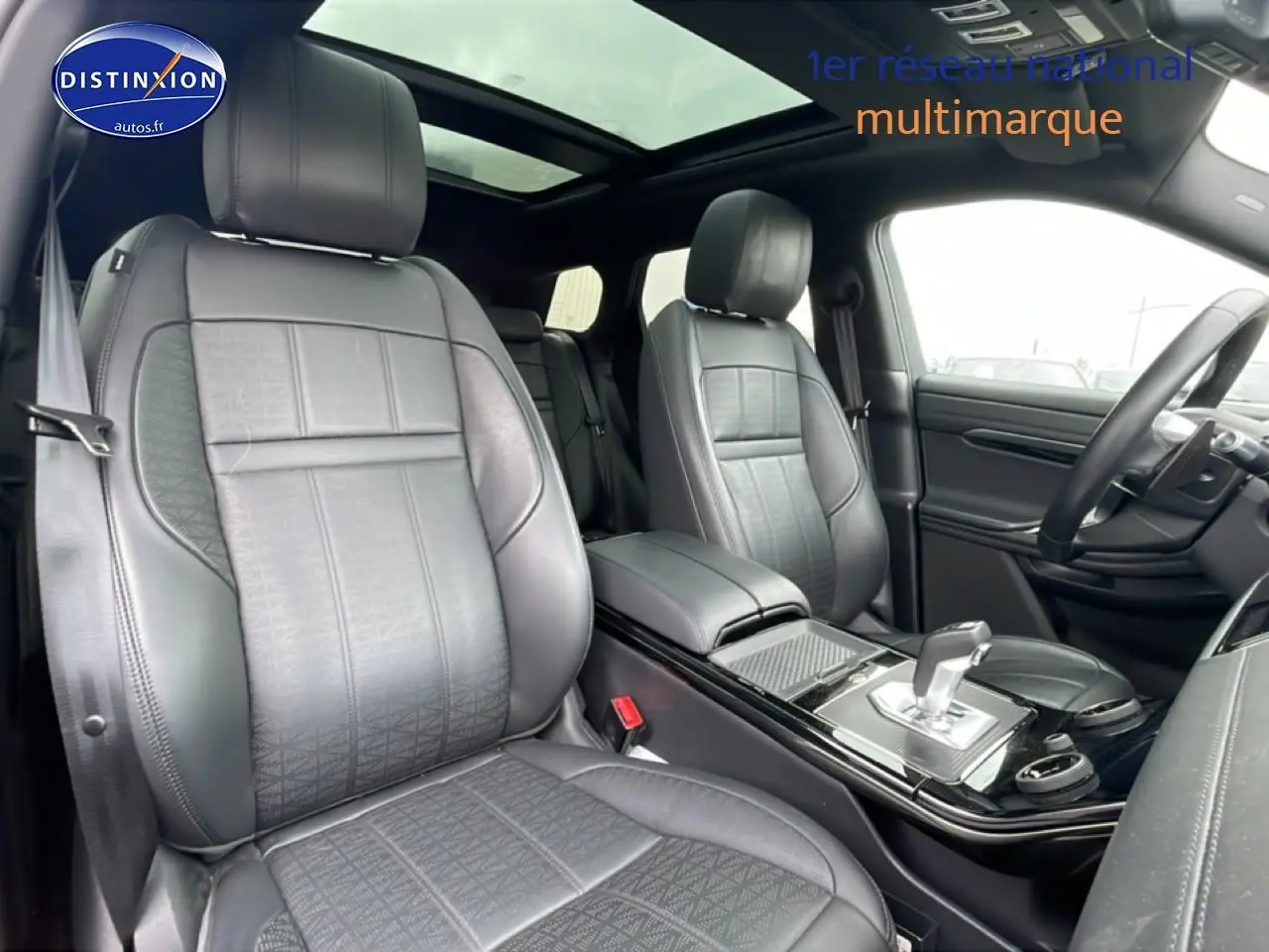 Vue intérieure avant du Range Rover Evoque 2020 noir, sièges cuir noirs et toit panoramique coulissant visible.